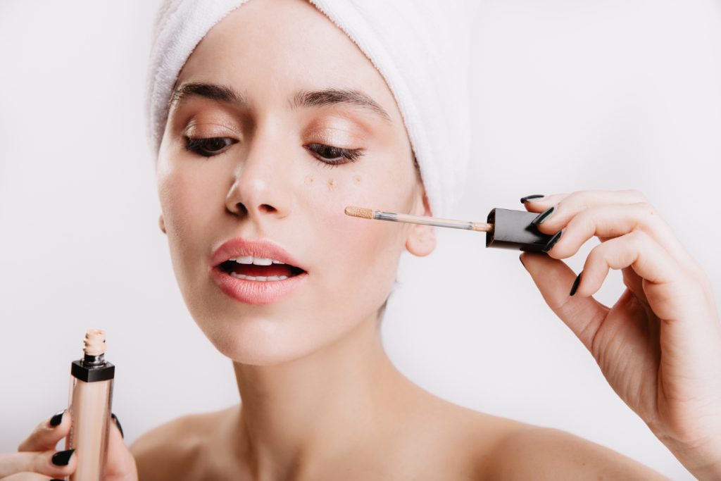 Femeie aplicând concealer sub ochi, cu sfaturi despre cum să alegi și să aplici cel mai bun concealer corect.