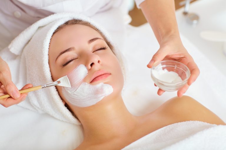 Prim plan al unei femei ce isi aplica un tratament facial cu crema