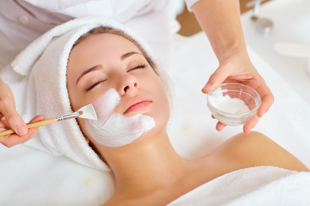 Prim plan al unei femei ce isi aplica un tratament facial cu crema