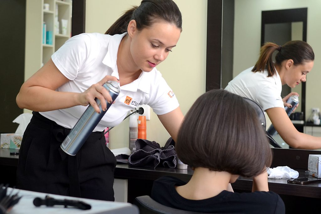 Stylist El Studio aplicând produs de coafat unei cliente într-un salon de înfrumusețare din România
